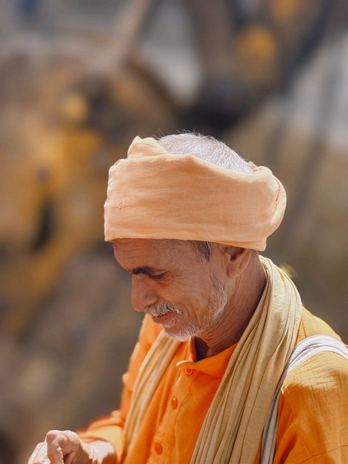 Free Elderly man in orange traditional outfit with a turban, captured outdoors in a warm setting. Stock Photo