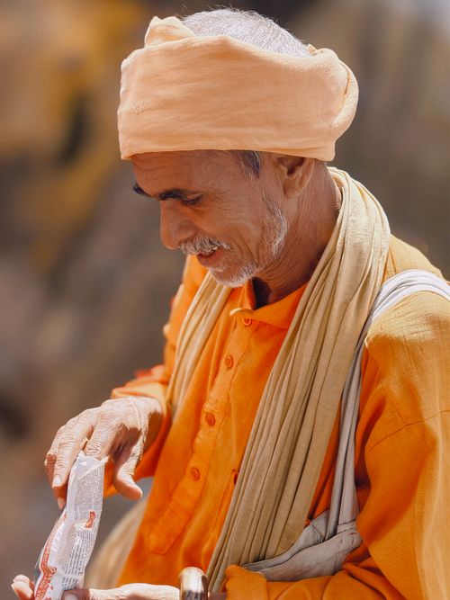 Free An elderly man dressed in traditional orange attire, engaged in an outdoor activity. Stock Photo