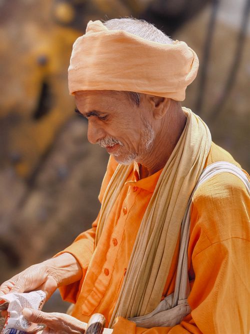 Free Elderly man in vibrant orange traditional attire and turban, captured outdoors. Stock Photo