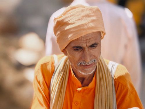 Free Portrait of an elderly man wearing traditional orange clothing outdoors. Stock Photo