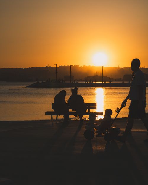 Free A family strolls by the Büyükçekmece shoreline during a vibrant Istanbul sunset. Stock Photo
