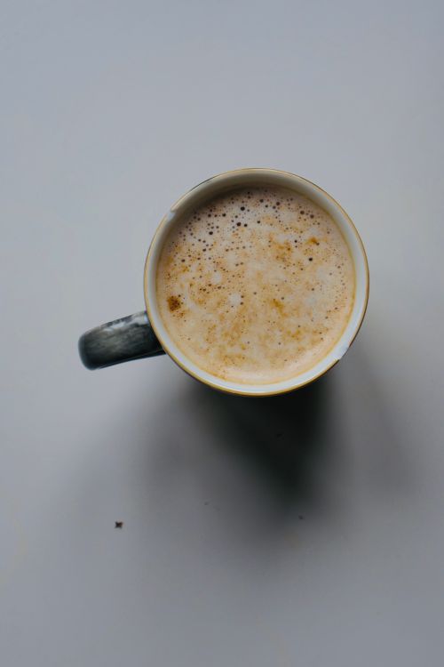 Free Aerial view of a coffee mug filled with creamy frothy coffee on a plain surface. Stock Photo