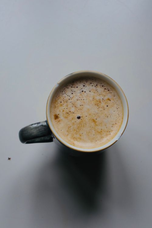Free Aerial shot of a frothy coffee in a ceramic mug on a plain surface. Stock Photo
