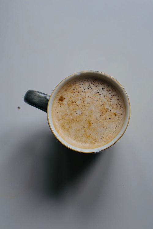 Free Aerial shot of frothy coffee beverage in a cup on a light surface. Stock Photo