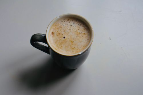 Free Cozy morning cappuccino served in a dark mug on a light background. Stock Photo