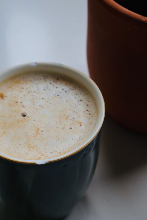 Free A creamy cappuccino in a ceramic mug placed on a table. Stock Photo