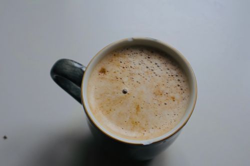 Free Close-up of a frothy coffee mug viewed from above, on a white table. Stock Photo