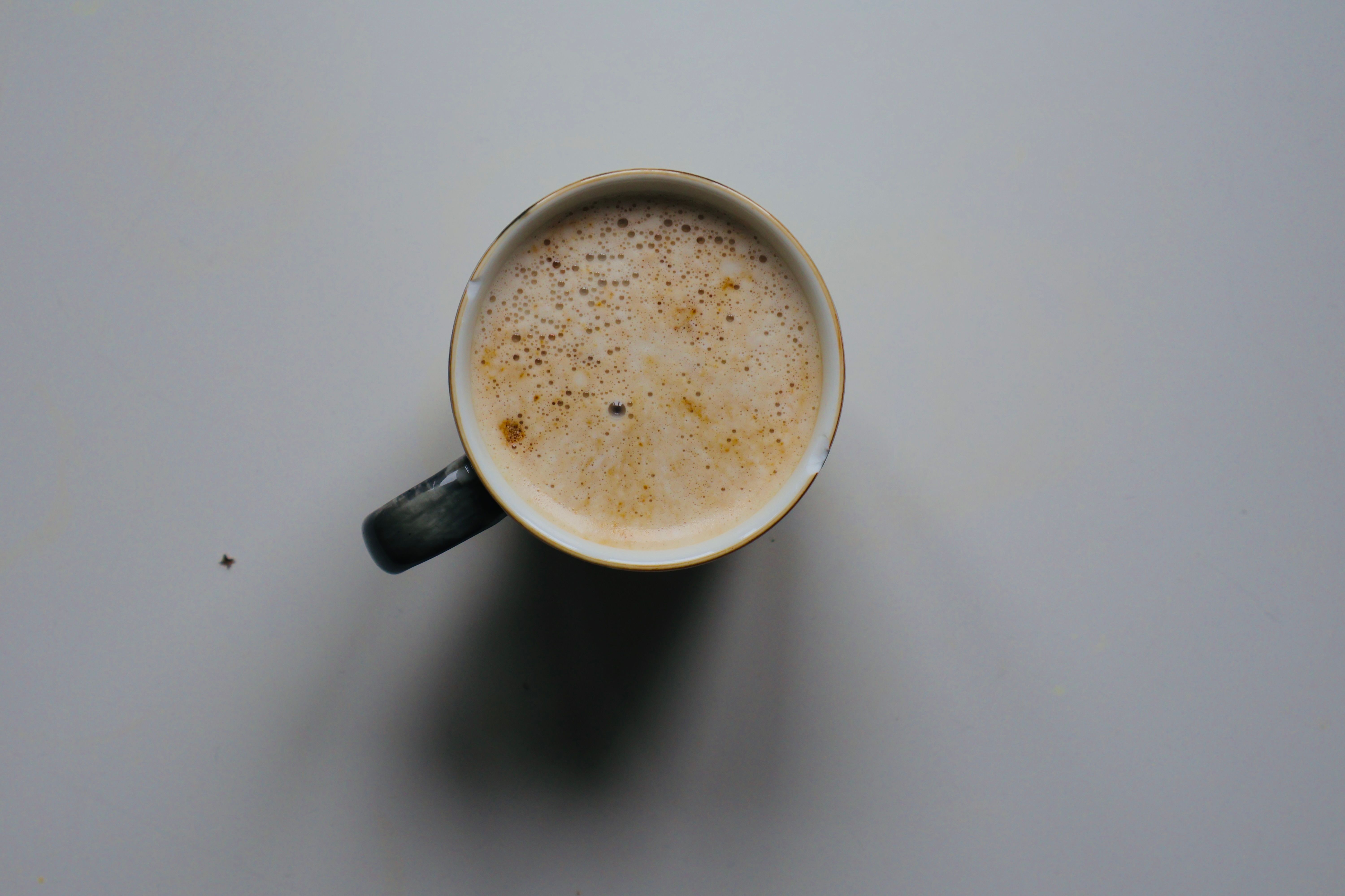 Top-down view of a cup filled with frothy coffee on a minimalist gray surface.