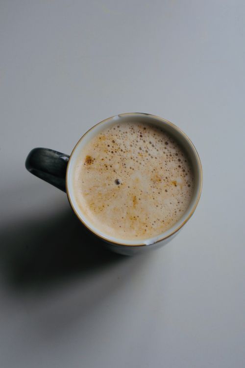 Free Aerial shot of a frothy cappuccino in a mug on a minimalist surface, perfect for coffee lovers. Stock Photo