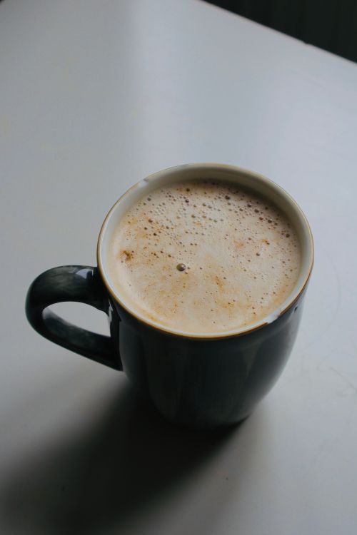 Free A soothing cappuccino with a foamy top served in a dark ceramic mug on a light surface. Stock Photo