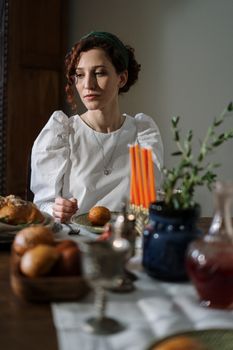 一位女子坐在精美的餐桌旁，桌上摆着传统的犹太美食和蜡烛