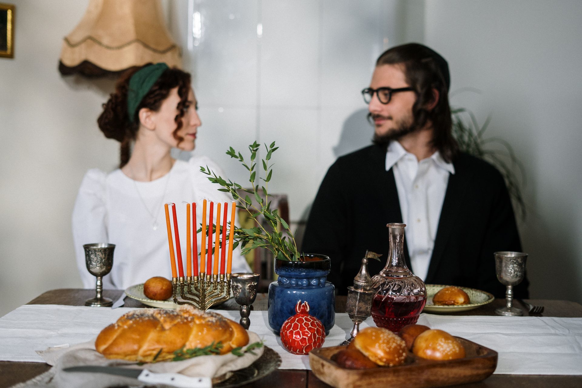 A Jewish couple enjoying a traditional Hanukkah meal with a menorah on the table.