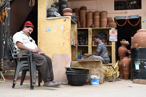 Free Two artisans at a pottery shop surrounded by clay pots and tools. Captures the essence of traditional craftsmanship. Stock Photo