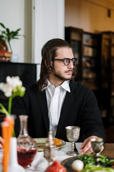Orthodox Jewish man enjoying a Shabbat meal with traditional symbols in a cozy dining room.