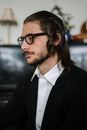 一位戴着眼镜、留着长发、头戴基帕的成年男性肖像，展现出体贴的举止