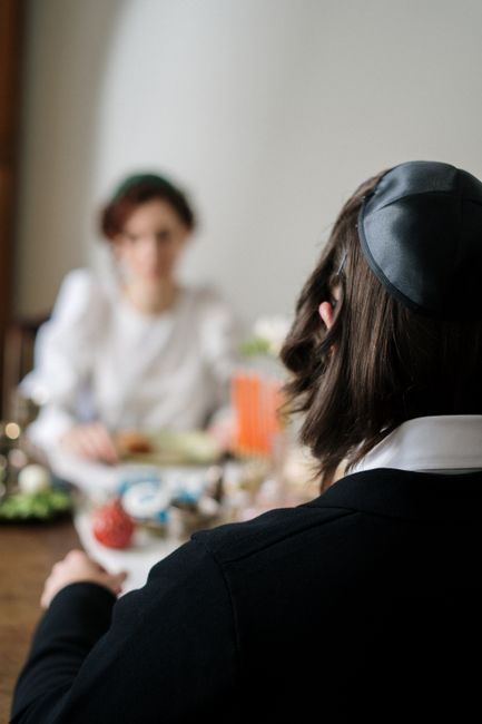 Orthodox Jewish couple sharing a festive meal at home, showcasing cultural tradition.