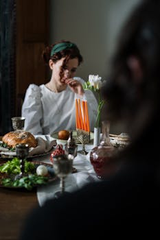 A woman at a beautifully set table for a traditional Jewish Shabbat celebration.