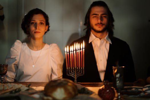 A couple enjoys a candlelit dinner celebrating Hanukkah with a menorah centerpiece.