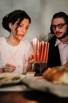 A Jewish couple lighting the menorah candles during a cozy Hanukkah celebration at home.