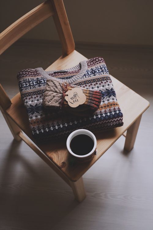 Free Warm knit sweater and coffee cup on chair symbolizes cozy fall vibes. Stock Photo