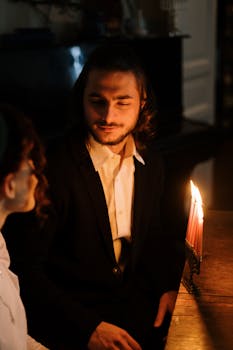 A couple enjoys a romantic candlelit evening celebrating Jewish traditions indoors.