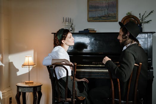 A couple sits by a piano in a warmly lit, cozy home.