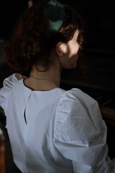 柔和的阳光下，一位穿着白衬衫的女人坐在室内，营造出宁静的氛围