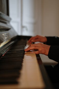 Close-up of hands playing piano indoors, illustrating a serene and cozy home vibe.
