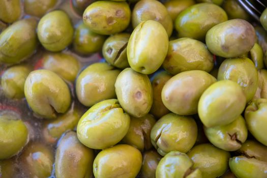 Close-up of green olives in liquid, captured at an İzmir marketplace.