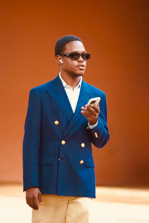 Free Confident man in sunglasses using a smartphone against an orange background. Stock Photo
