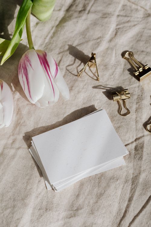 Free A serene flat lay of tulips, paper clips, and blank sheets on textured fabric. Stock Photo
