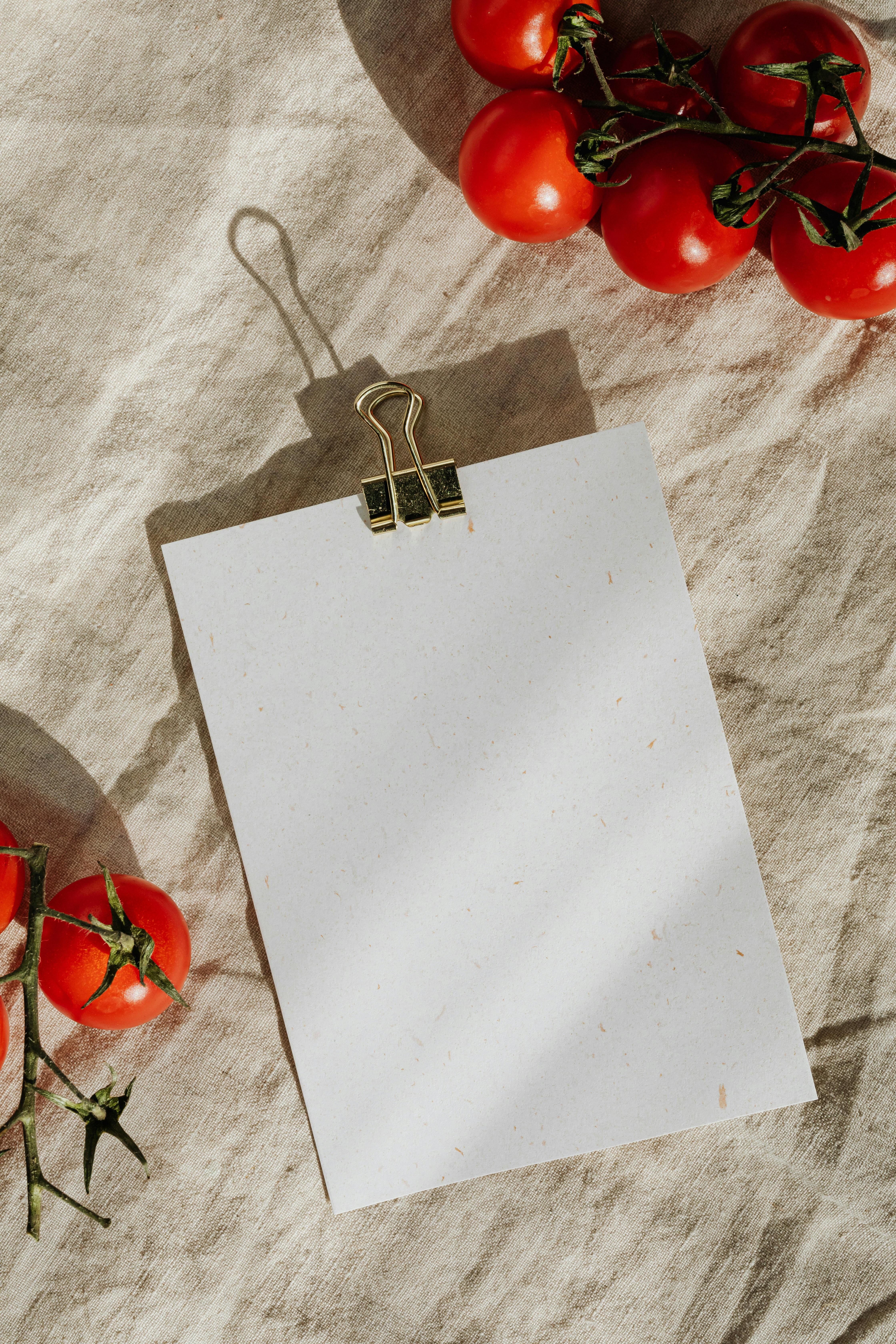 A blank sheet with tomatoes on a textured linen background, ideal for culinary themes.