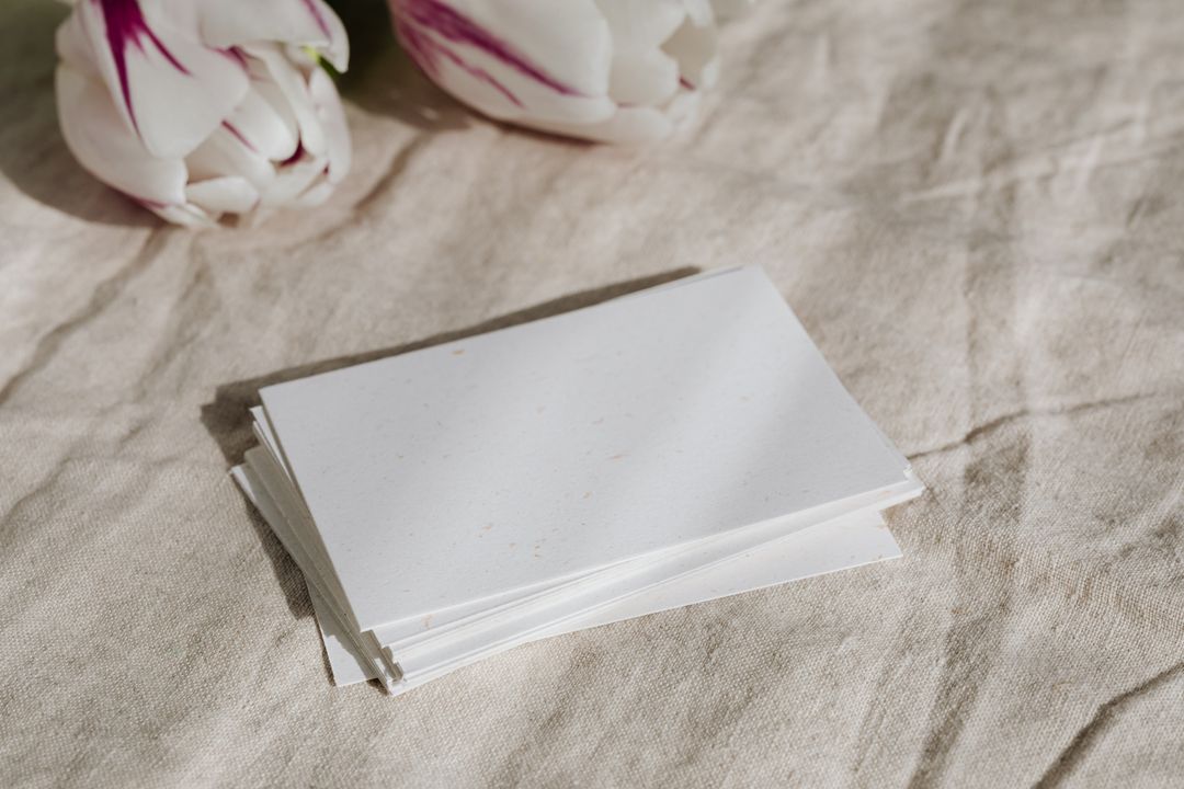 A simple stack of papers on beige fabric with tulips, ideal for stationery displays.