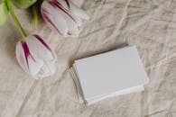 亚麻织物上，特写的紫色郁金香旁边有一张空白卡片