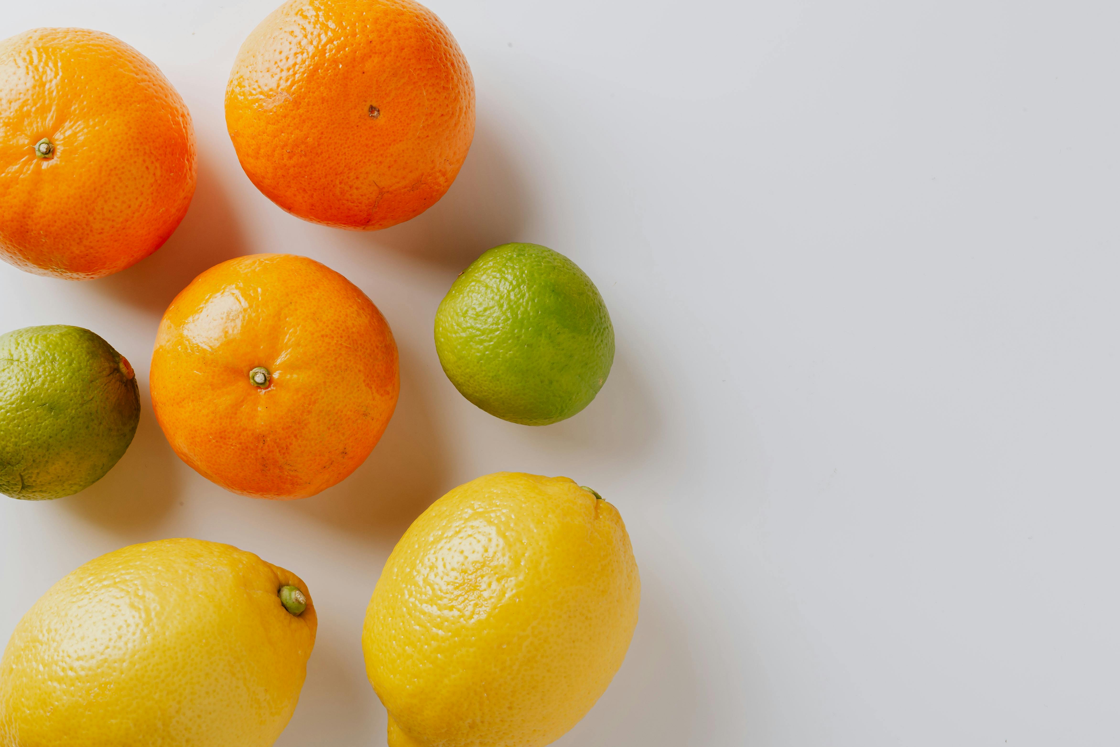 Free Vibrant assortment of citrus fruits including lemons, limes, and oranges on a white background. Stock Photo