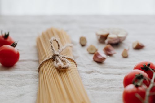 Free Uncooked spaghetti with cherry tomatoes and garlic on a rustic cloth setting. Stock Photo