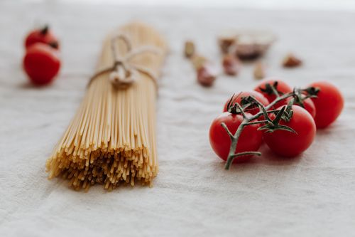 Free Aesthetic flat lay of dry spaghetti and fresh tomatoes on a linen backdrop. Stock Photo