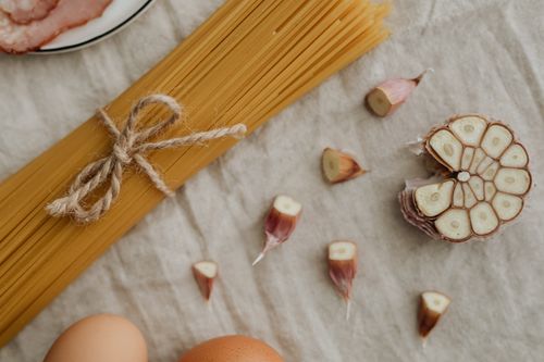 Free Flat lay of uncooked spaghetti, garlic, and eggs on a rustic table setting. Stock Photo