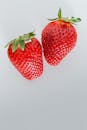 白色背景上，两个成熟的草莓以充满活力的红色展示着新鲜