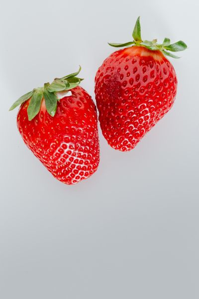 Two ripe strawberries on a white background — photo by Kaboompics on Pexels
