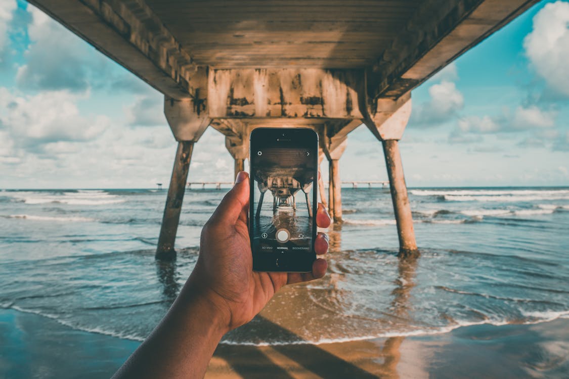免费 拿着i Phone的海边沙滩码头下的人 素材图片