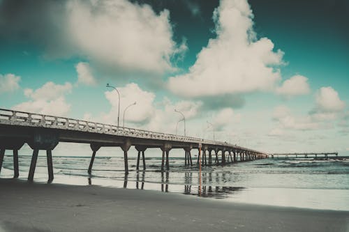 White Clouds and Gray Concrete Bridge Near at Seashore