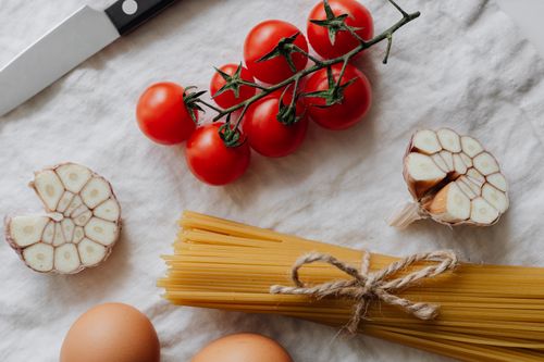 Free Top-down view of fresh ingredients for a classic pasta dish, featuring cherry tomatoes, garlic, and spaghetti. Stock Photo