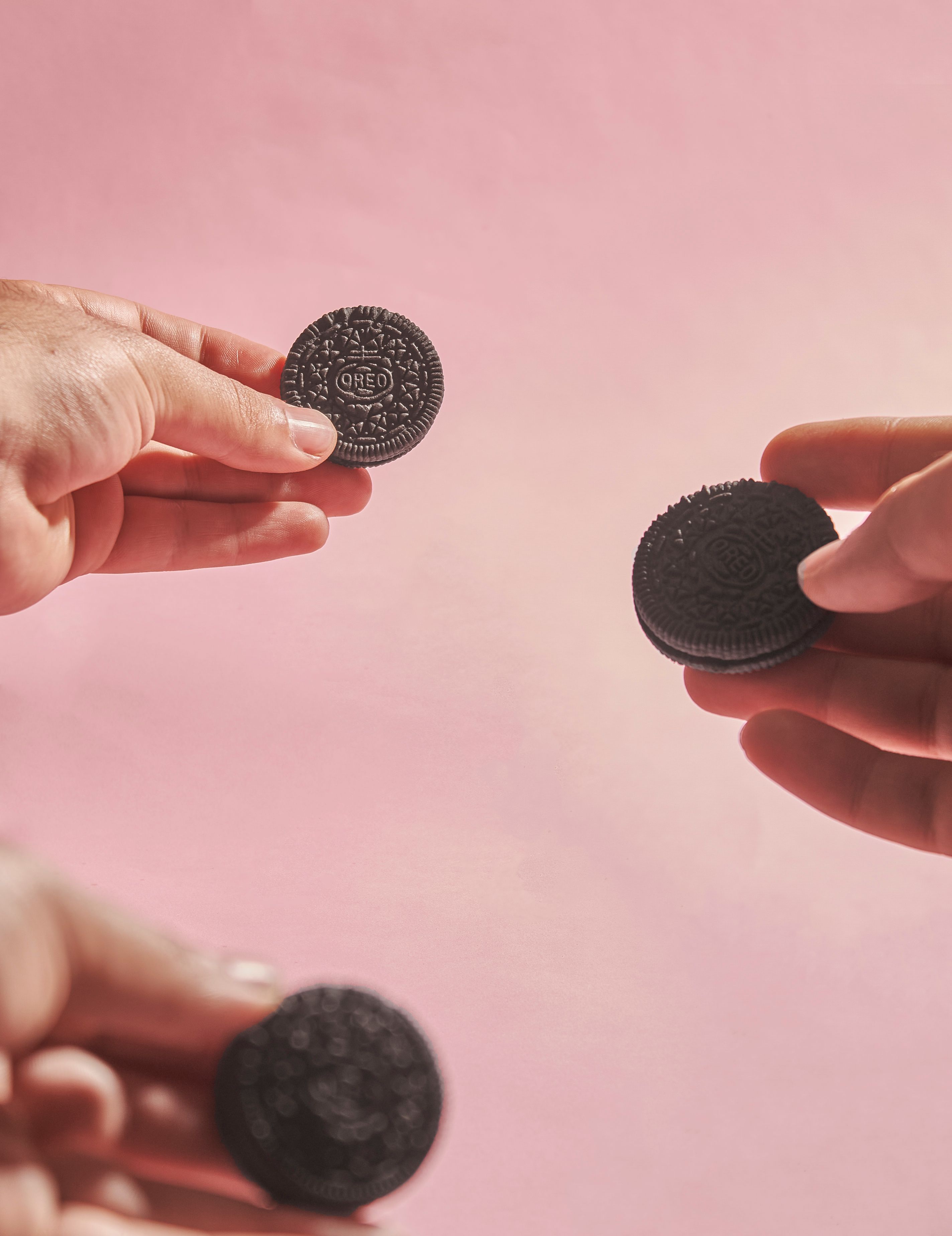 Hands Holding Chocolate Sandwich Cookies on Pink Background · Free ...