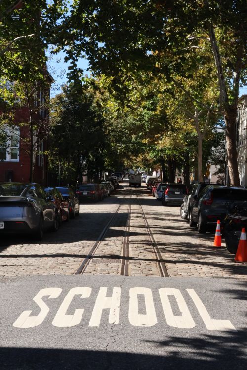 Free Urban street scene featuring school sign and parked cars under sunny skies. Stock Photo