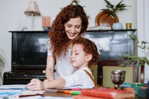 Free A mother assists her young son with his homework, fostering a loving and educational environment. Stock Photo