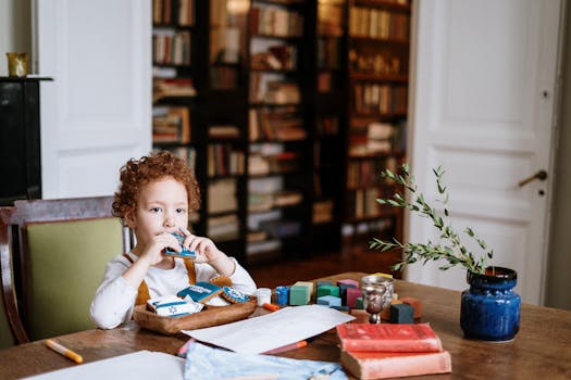 A child with curly hair enjoying Hanukkah cookies at a table in a cozy home library.