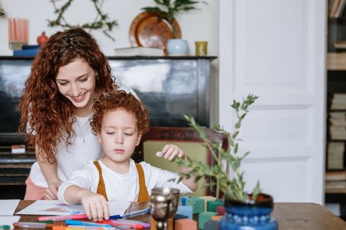 Free A joyful mother and son drawing together at home, surrounded by colors and creativity. Stock Photo