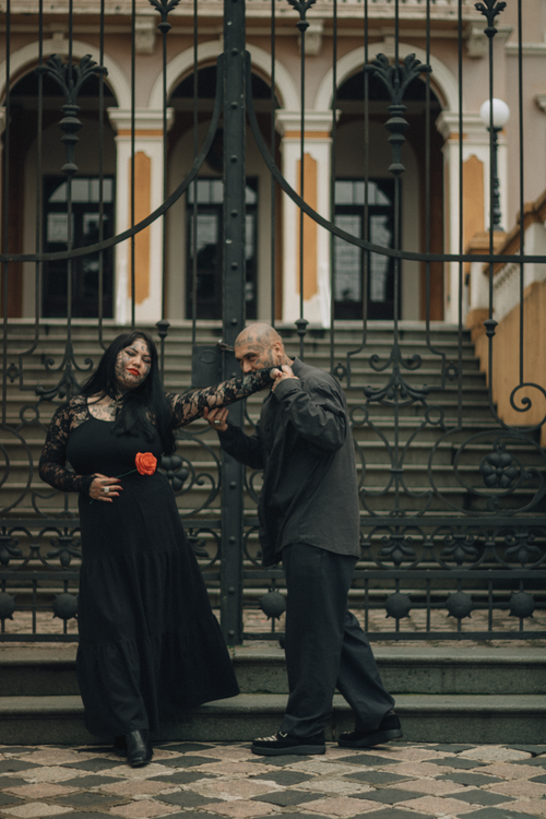 Free Couple in gothic attire posing dramatically in front of an ornate iron gate. Stock Photo