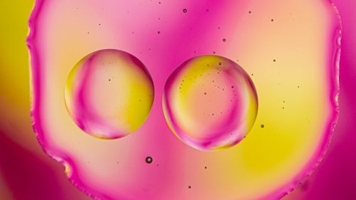 Free Colorful abstract art featuring pink and yellow oil droplets in a macro view, creating a surreal effect. Stock Photo